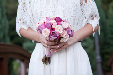 Beautiful wedding bouquet in bride`s hands. Stylish bride with a bouquet of roses