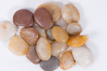 pebbles. clean white brown black pebbles isolated. the pebbles are on white or brown sand. small and large are visible