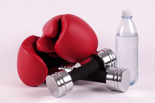 A pair of boxing gloves and dumbbells and a bottle of water. Ready for a hard fight workout. Concepts for martial arts, boxercise, gym and workout, etc.