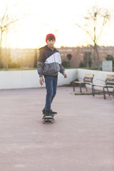 Skater-teenager wearing a hat boarding on the street