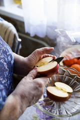 Obraz na płótnie Canvas Granny cuts Apple in the kitchen