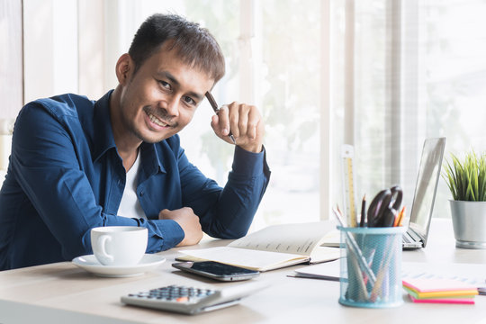 Happy Handsome Asian Business Entrepreneur Smiling And Working On The Desk In His Home. Successful Young Businessman In E Commerce Manage His Order To Sent Parcel By Post At Home.