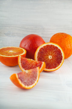 fresh ripe blood oranges, slices, rustic food photography on white wood plate kitchen table can be used as background