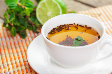 cup of black tea with mint leaves on a wooden table