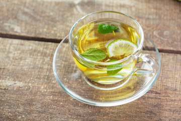 cup of black tea with mint leaves on a wooden table