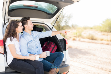 Couple in car trunk looking at something interesting