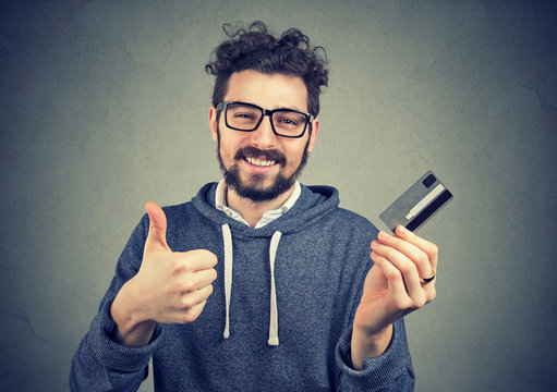 man holding a credit card showing thumbs up