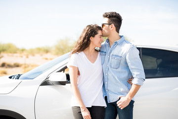Romantic couple standing by their car outdoors