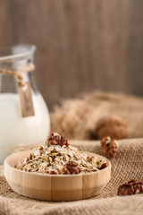 Dry rolled oatmeal in wooden bowl on textile background.