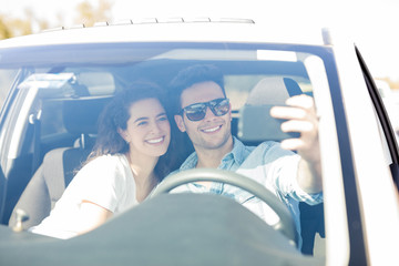Loving couple taking selfie in a car