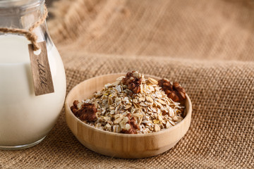 Dry rolled oatmeal in wooden bowl on textile background.