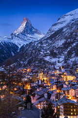 The world-famous Matterhorn glows in the early morning above the Swiss village of Zermatt, as the sun prepares to rise over the Alps. - obrazy, fototapety, plakaty