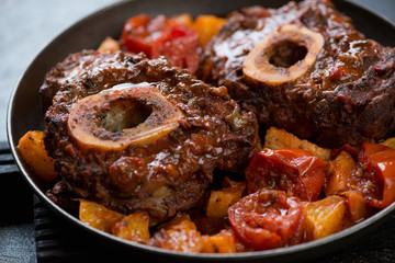 Closeup of osso buco made of cross cut veal shank with oranges and tomatoes, selective focus,...