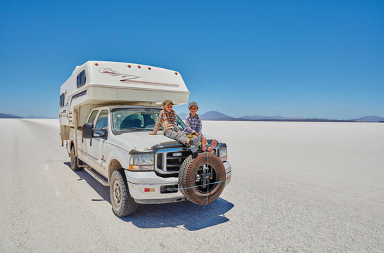 Two boys sitting on parked recreational vehicle, Salar de Uyuni, Uyuni, Oruro, Bolivia, South America