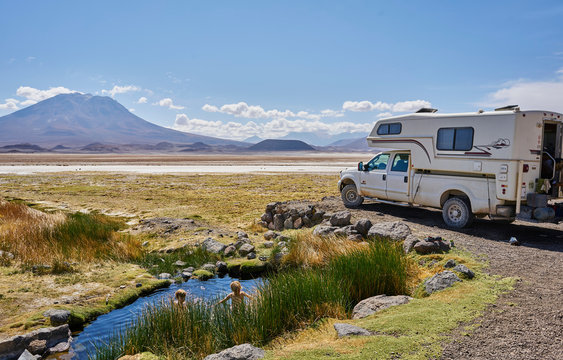 Two boys playing in water pool beside parked recreational vehicle, Salar de Chiguana, Chiguana, Potosi, Bolivia, South America
