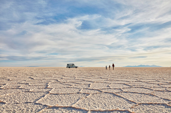 Mother and sons walking across salt flats, recreational vehicle in background, Salar de Uyuni, Uyuni, Oruro, Bolivia, South America