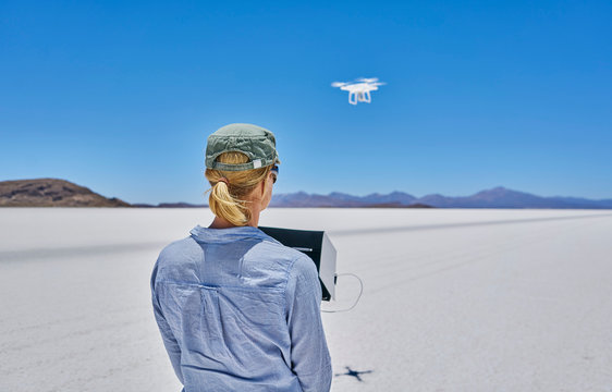 Woman on salt flats, flying drone, rear view, Salar de Uyuni, Uyuni, Oruro, Bolivia, South America
