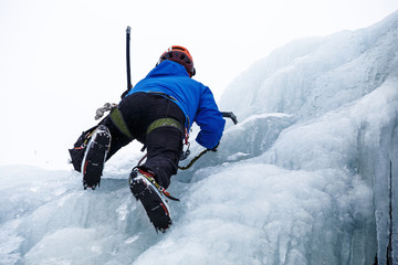 Fototapeta na wymiar Rock climber climbs a frozen waterfall.