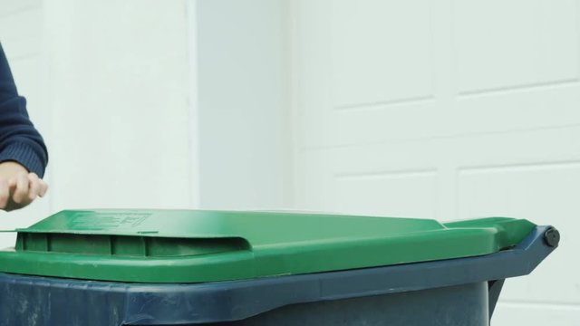 To throw a bag of garbage in the garbage can, close-up