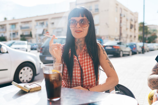 Mature female hipster smoking cigarette at sidewalk cafe