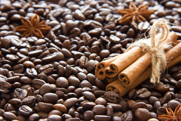 The roasted coffee beans are scattered and a bunch of cinnamon sticks and anise