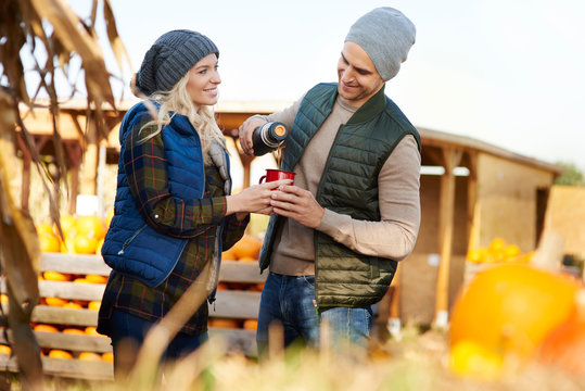 Couple pouring coffee from flask at pumpkin patch