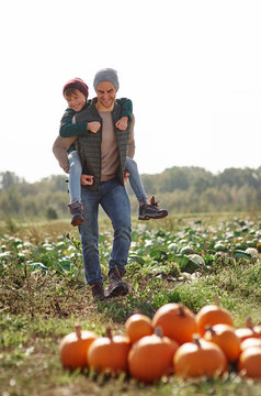 Man giving son piggyback ride in field at pumpkin patch