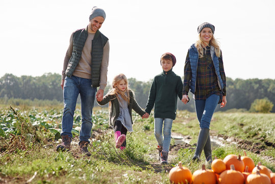 Couple holding hands with son and daughter in pumpkin patch field