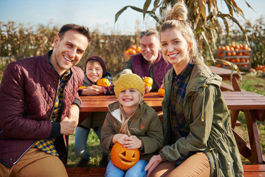 Portrait of three generation family at pumpkin patch picnic table