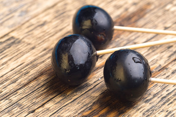 three grapes on toothpicks lie on a natural wooden background