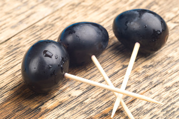 three toothpicks on which are strung grape berries, natural wooden old background