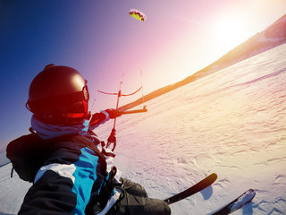 Selfie action camera Skier with kite rides on frozen lake on free ride. Russia. Snowkite sunset.