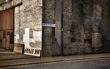 Vintage look corner of Loftie street in Southwark, London with dirty old brick wall.