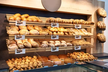 Rolgordijnen Vers brood en gebak op planken in bakkerij © Sergey Ryzhov