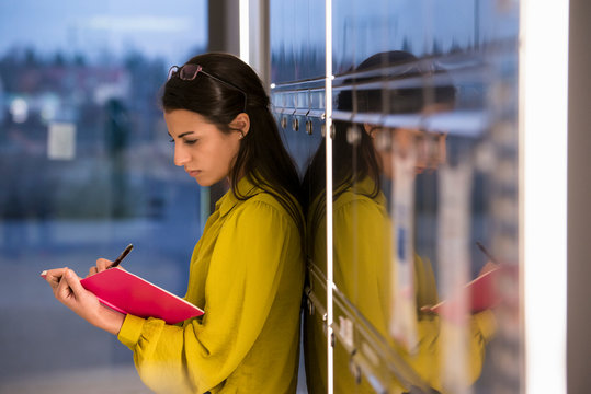 Woman writing in notepad at office - Powered by Adobe