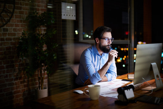 Young businessman looking at computer on office desk at night