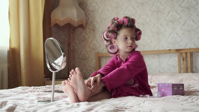 Charming little girl with curlers in pink dress