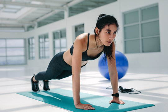 Strong woman doing push ups on mat
