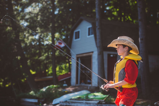 Boy in cowboy hat fishing from lakeside