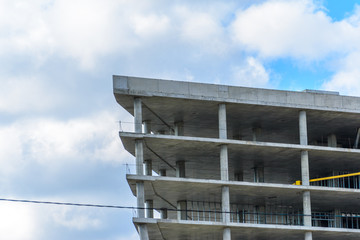 Fototapeta premium Reinforced concrete skeleton of an unfinished building against the background of a cloudy sky