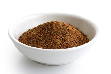 Ground cloves in white ceramic bowl isolated on white.