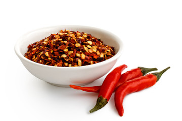 Coarsely ground chilli peppers in white ceramic bowl isolated on white. Fresh chillies.