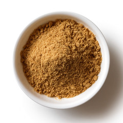 Finely ground dry ginger in white ceramic bowl isolated on white from above.