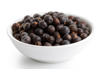 Dried juniper berries in white ceramic bowl isolated on white.