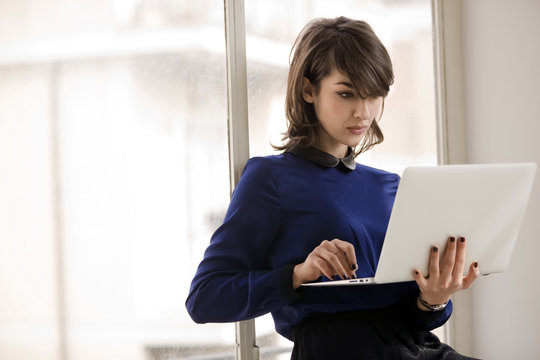 Focused young businesswoman uses a laptop in an office.