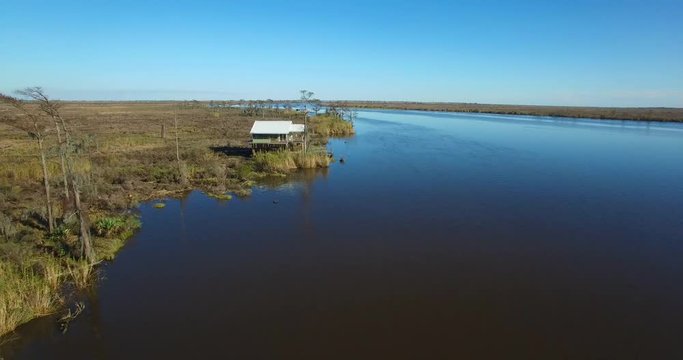 An aerial over the Louisiana bayou reveals a house on stilts.