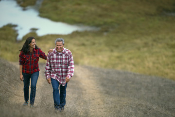 Mature couple walking on a grassy path.