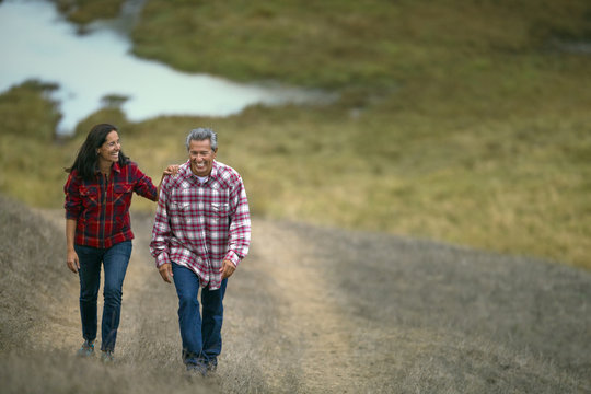 Mature couple walking on a grassy path.