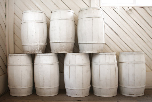 Pile of white painted barrels insite a white wooden room