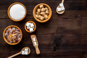 Sugar types. Cane, refind, granulated, cubes, candy sugar. Dark wooden background top view copy space